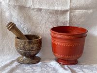 Side view of wooden mortar and pestle next to red lacquerware bowl