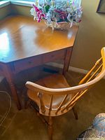 Photo of wooden corner desk with angled front and two small drawers, surface has flower arrangement.