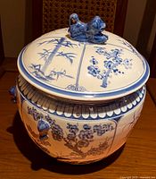 Close-up of large blue and white Asian themed casserole lid with sculpted animal figure and floral bamboo patterns