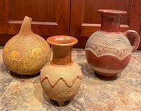 Front view of the carved gourd vase and two clay pots showing details of their surface decorations and shapes.