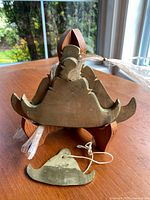 Photo showing the wooden stand with one flat bell placed on the table, viewed at an angle near a window.