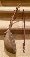 Wooden stringed instrument with pear-shaped body and tuning pegs on angled neck, bow included