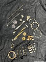 Photo showing full array of mixed metal costume jewelry laid out on dark fabric including necklaces, earrings, bangles, bracelets, and brooches.