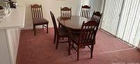 Dining table with six chairs arranged around it, showing the table's surface and chair style.