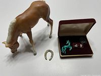 Photo of brown foal model horse with cream mane and tail (tail detached) and a burgundy box containing horse-themed jewelry.