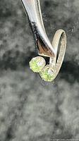 Close-up image of the sterling silver ring with two bright green peridot gemstones.