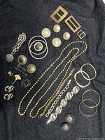 Top view photo showing the assorted jewellery items laid out on black fabric, including earrings, bracelets, bangles, buckles, locket, and the Chinese fan