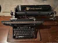 Top view showing the full Underwood typewriter mounted on a wooden board, with visible keys and metal parts.