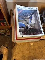 A stack of Architectural Digest magazines viewed from the top, showing a magazine with a blue sky and organic architectural design on the cover.