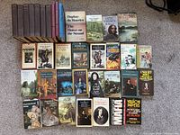 Top-down view of the entire collection of 31 books including various cloth-bound editions and paperbacks arranged on a carpeted floor.