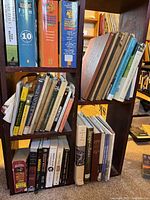 Books on wooden shelves showing a mixed lot of hardcover and paperback books in a range of subjects.
