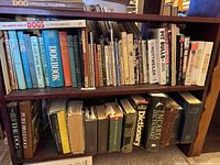 Photo of multiple shelves filled with books primarily about dogs including breed guides, dog training, and general dog knowledge books. Some books are older and some are in hardcover and paperback.