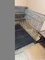 Black metal collapsible dog crate set up, showing the side and top wireframe along with the black plastic tray at the bottom.