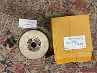 Silver metallic rotor/flywheel and small associated metal parts alongside labelled cardboard box for Harley Davidson alternator.