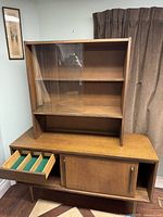 Full front view of the hutch showing upper glass sliding doors, two shelves inside, and pull-out drawer below with green felt drawer compartments.