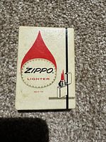 Photo of original Zippo lighter box with branding and flame logo.