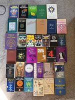 Grid of 30 occult and magic books arranged on carpet showcasing top view of covers