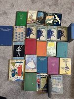 Top view of 22 vintage children's books arranged on carpet showing titles such as 'Dimple Moves Up Again', 'The Winged Horse', and 'Masquerade at the Wells'
