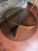 Top view of round smoked glass tabletop and wood base partially visible