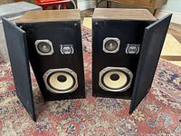 Two Hitachi speakers with fabric covers removed showing tweeter and woofer.