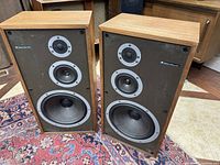 Front view of two Celestion Ditton 442 speakers showing the wood veneer cabins and three drivers (woofer, mid-range, tweeter) on each.