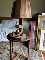 Full view of the wooden table lamp placed on a small wooden side table with decorative brass teapot figurines on the lamp base.