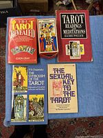 Overhead view of five items placed on blue cloth: The Tarot Revealed book, Tarot of Marseilles deck box, Tarot Readings and Meditations book, The Symbolism of the Tarot book, The Sexual Key to the Tarot book