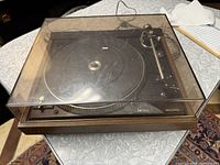 Photo of the Dual CS 506-1 turntable with the dust cover closed, showing the wood finish base and transparent cover.