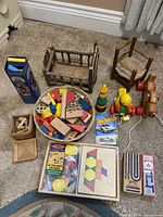 Photo showing wooden cradle, chair, colorful wooden blocks on plate, small box with wooden pieces, and pull toys (duck and snake).