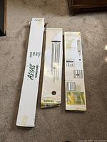 Three boxed wind chimes on carpeted floor, showing original packaging from Arias and Humboldt Acoustic brands.