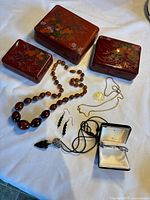 Overall shot of three lacquer boxes and jewellery laid out