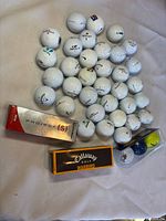 Pile of loose white golf balls with three boxed sleeves visible