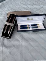 Both boxed pen sets side by side, showing exterior cases and pens