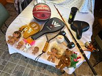 Overall lot showing basketball, racquet, rod & reel, bike seat, tennis balls, cribbage board, troll dolls and other small items