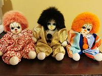 Group shot of all three Q-Tee porcelain clown dolls seated on shelf