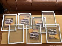 Overview of seven white floating frames on table, some wrapped