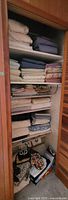 Full view of closet shelves filled with folded linens in various colors and patterns.