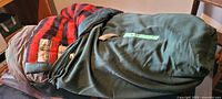 Sleeping bag rolled/unrolled showing green canvas exterior and red/black wool lining