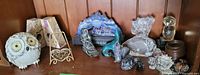 Wide view of the shelf displaying all the various home decor items including ceramic owl, amethyst bookends, metal dish on stand, glass animal figurines, crystal flower, and metal candle holder.