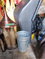 Bird feeder with copper top, scoop shovel behind it, and metal can on the floor