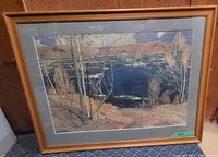 Framed landscape print showing lake with trees and hills in autumn colors, in honey pine frame.