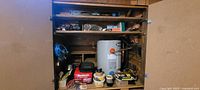 Wide shot of tool cupboard containing various tools including an electric water heater or paint sprayer, battery charger, and miscellaneous hand tools.