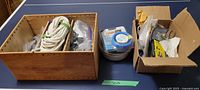 Wooden and cardboard boxes holding assorted hardware and tools on a blue surface