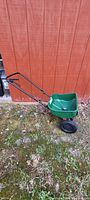 Side view of Scotts Turf Builder green weeder spreader showing handle, hopper and wheels.