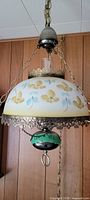 Full view of vintage hanging lamp suspended, showing painted floral glass shade, brass chains, and brass fixtures.