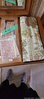 Photo of closed floral-patterned needlework needle case with craft samples and green lot tag