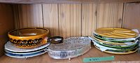 Photo showing the six gold and green vintage ceramic plates stacked with the pickle tray featuring a silver cover and clear patterned glass base.