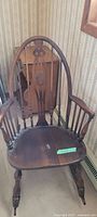 Front view of the vintage brown wooden rocking chair showing the seat, arms, and legs