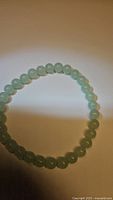 Close-up image of natural green aventurine beads on a stretchy bracelet, showing bead size and color.