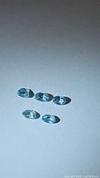 Five oval cut blue gemstones on a white background, displaying clarity and consistent color.